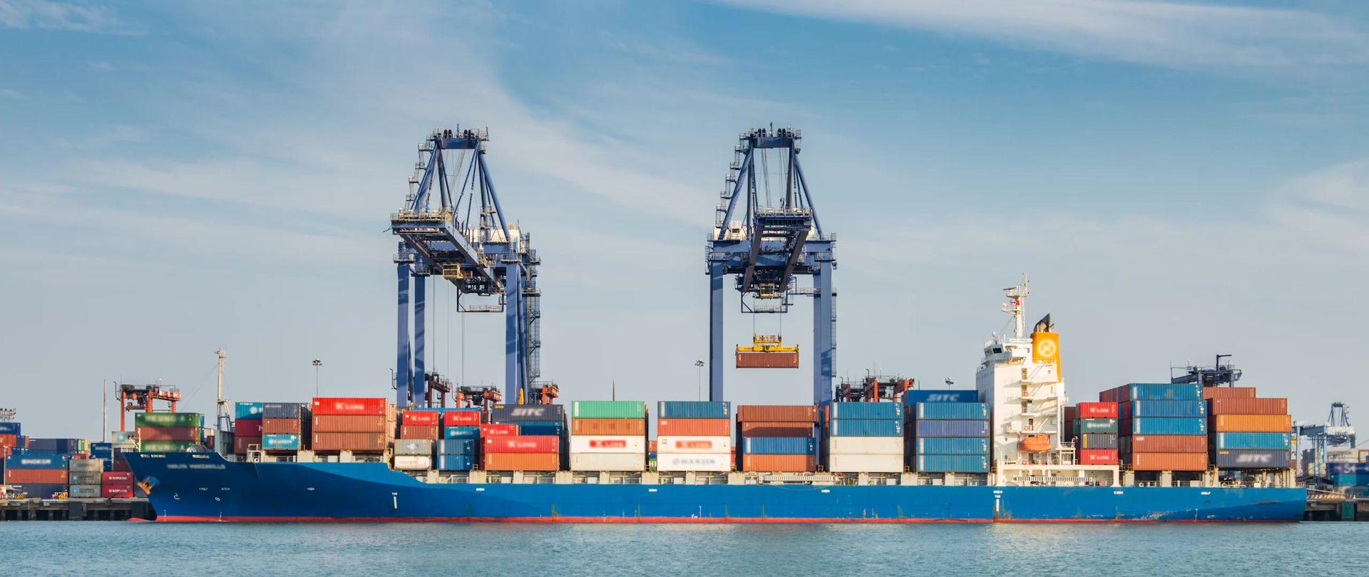 Container ship at port beneath gantry cranes